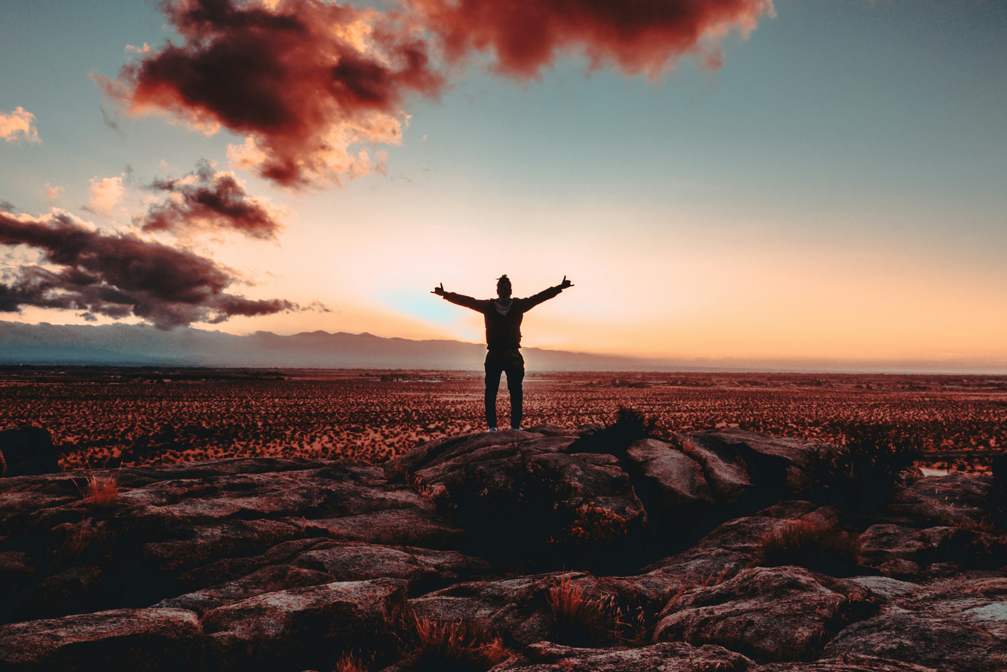 Person standing on rock raiding both hands